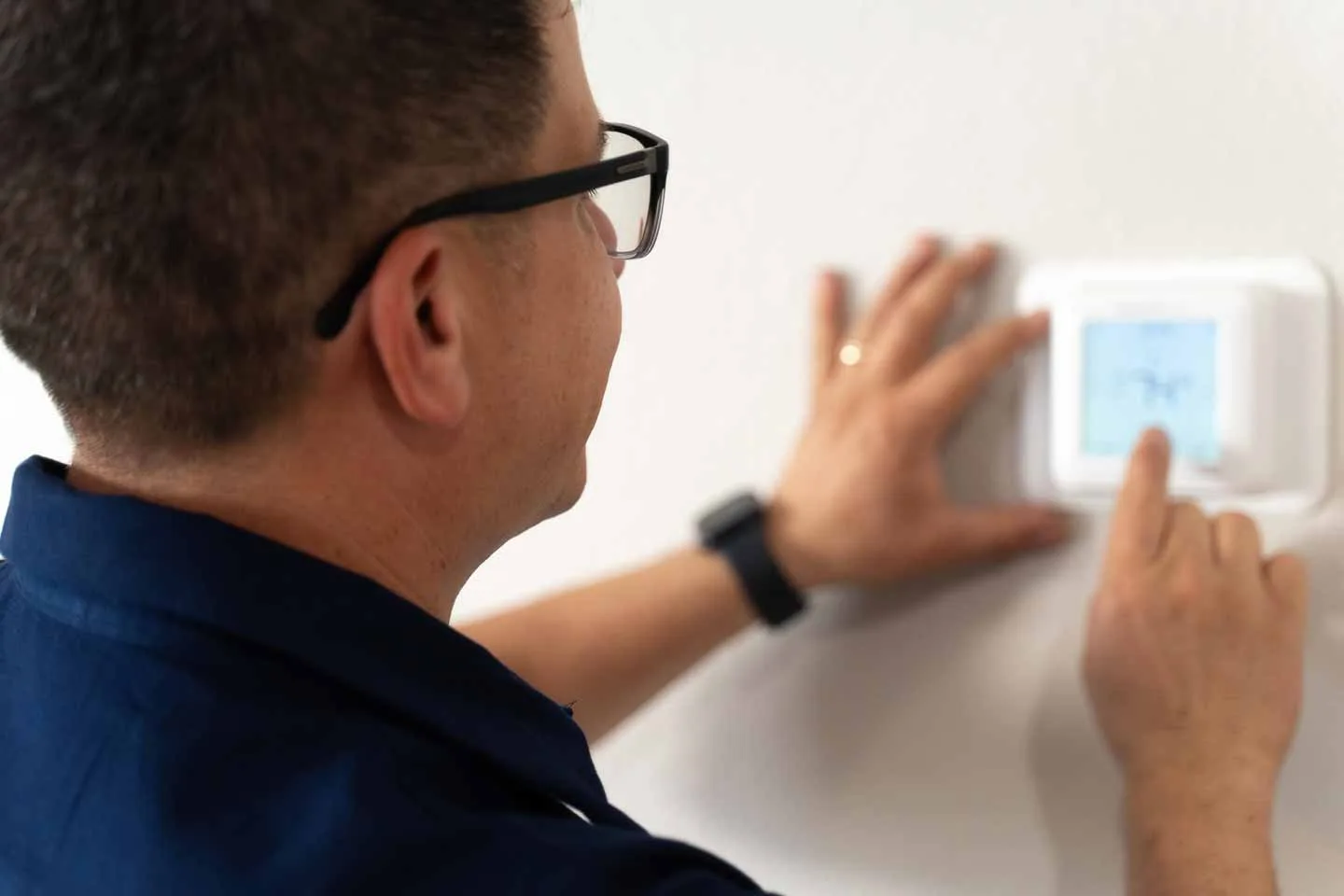 Technician repairing smart thermostat in Houston TX